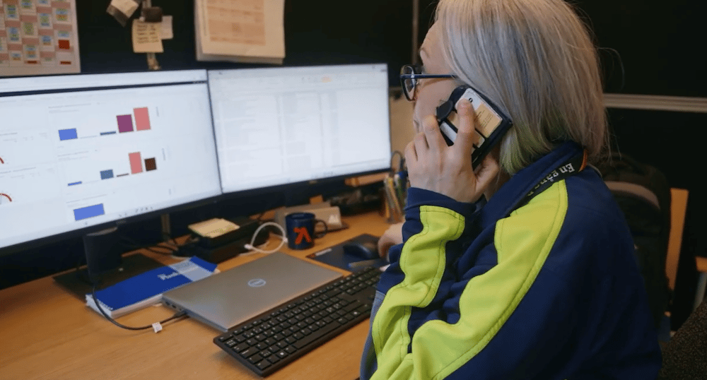 en person som pratar i mobiltelefon framför en dator
