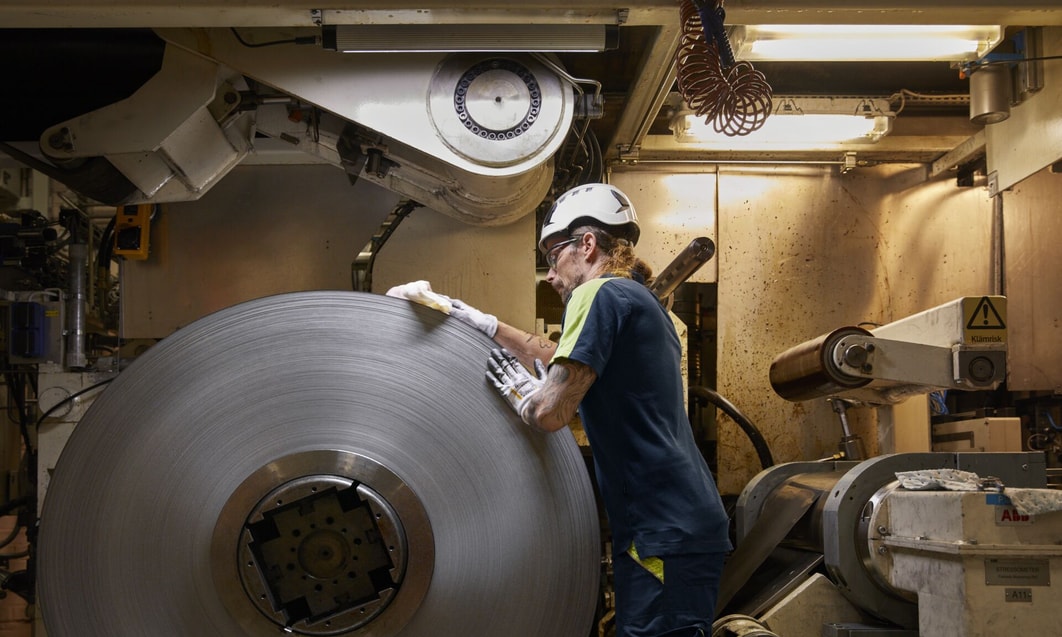 a person in a hard hat working on a large round metal object
