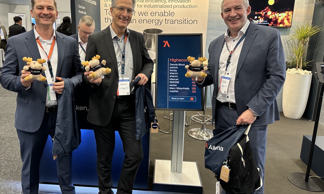 a group of men standing in a room with a sign and a teddy bear