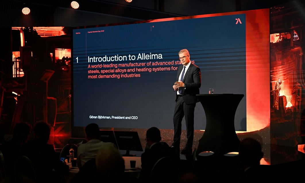 a person standing on a podium with a large screen behind him