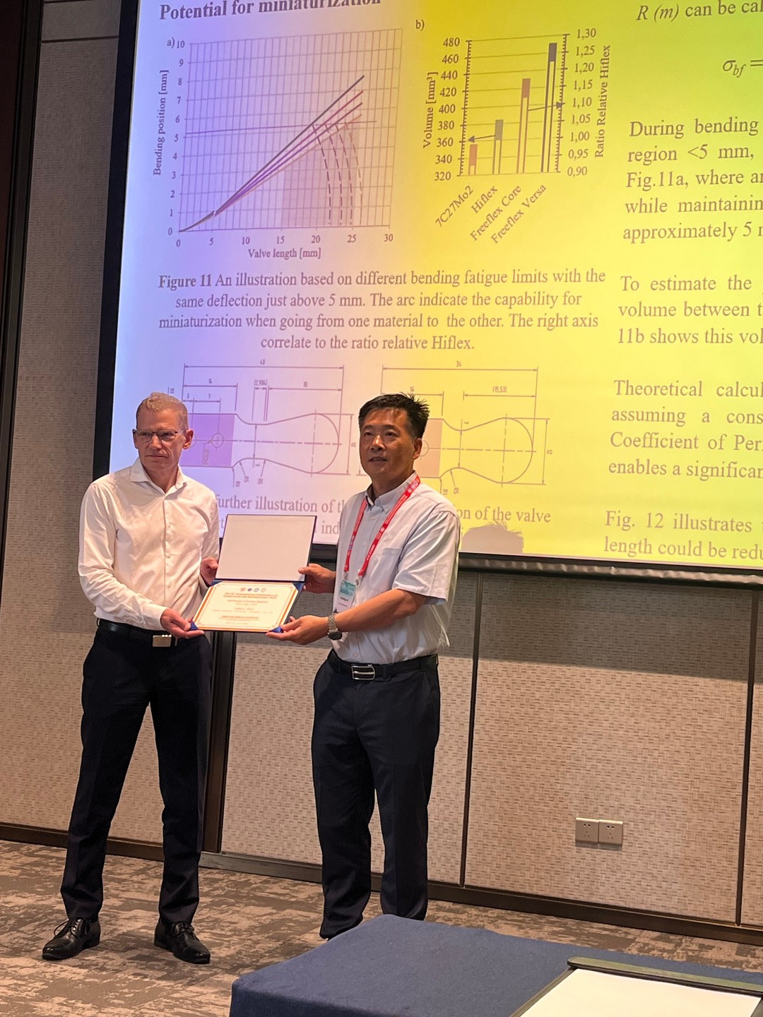 a person holding a certificate and standing in front of a large screen