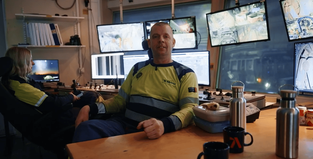 en person som sitter vid ett skrivbord med flera skärmar
