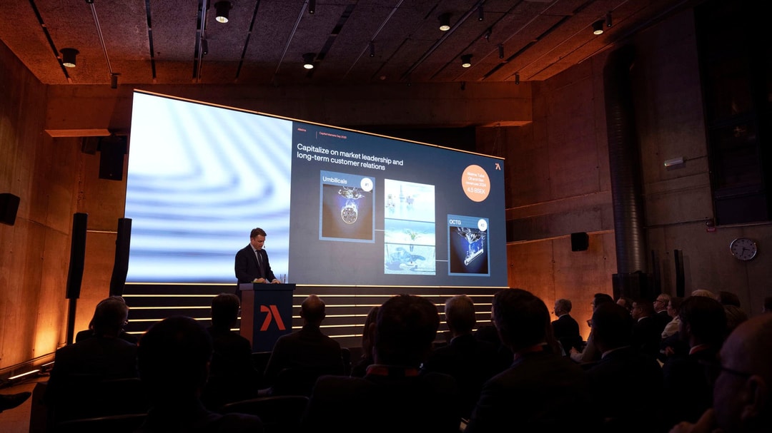 a person standing at a podium with a large screen on the stage