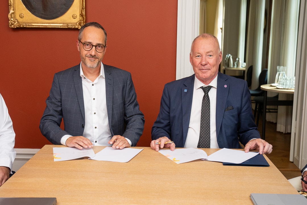 två män sitter vid ett bord med papper