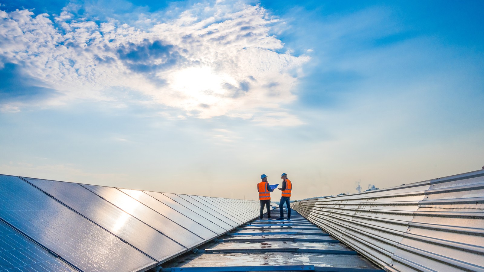 two men standing on a roof with solar panels