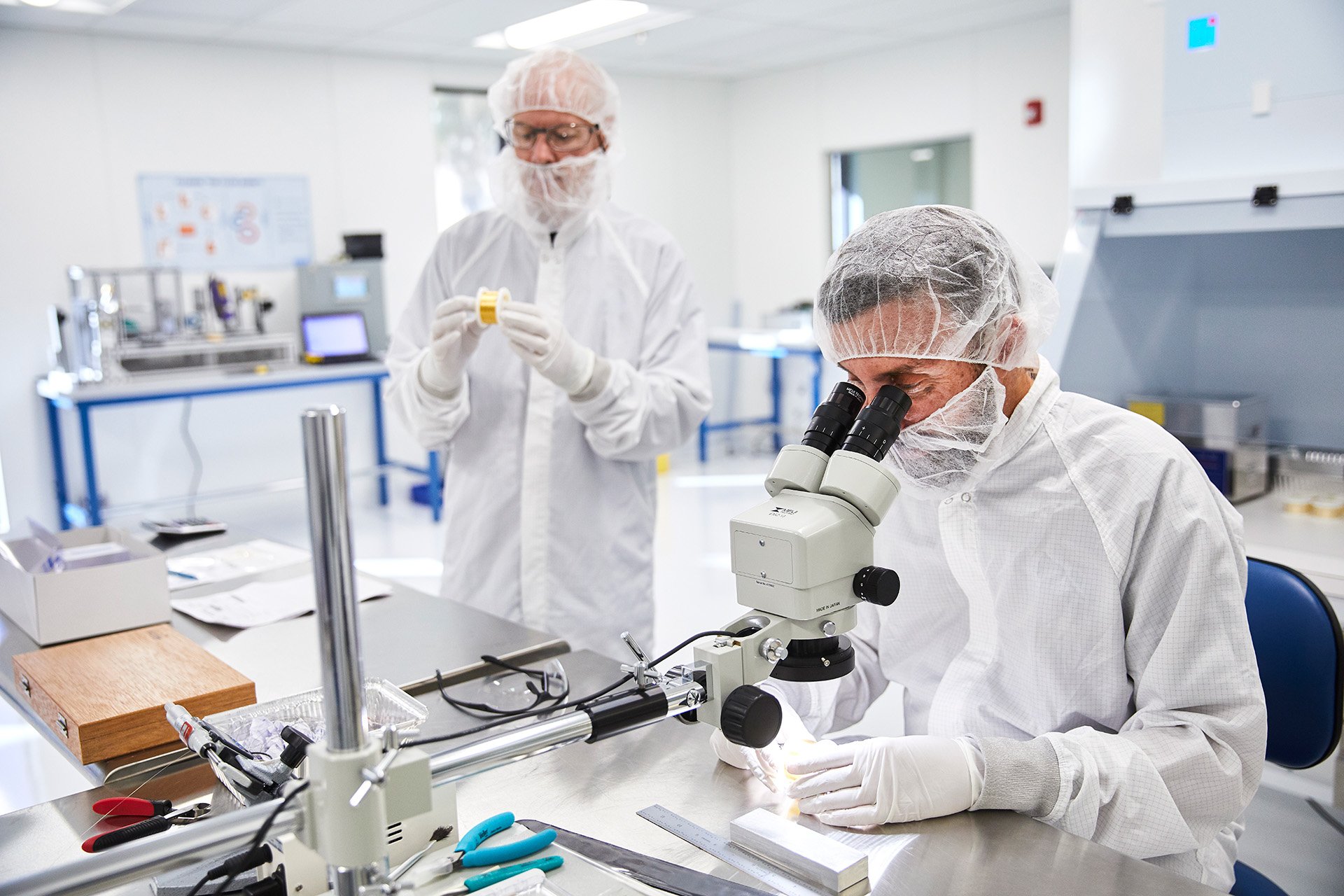 a group of people in white coats looking through a microscope