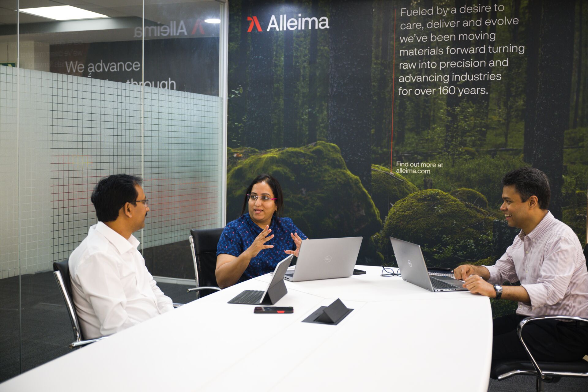 a group of people sitting around a table with laptops