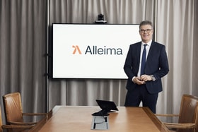 a person in a suit standing in front of a screen