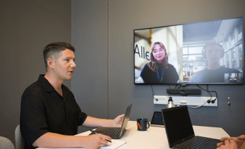 en person som sitter vid ett bord med en bärbar dator och en bärbar dator på den