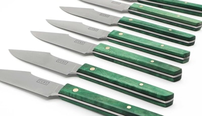 a row of knives with green handles