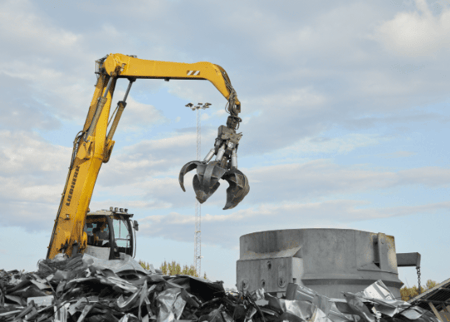 a yellow construction vehicle with a claw holding a metal object