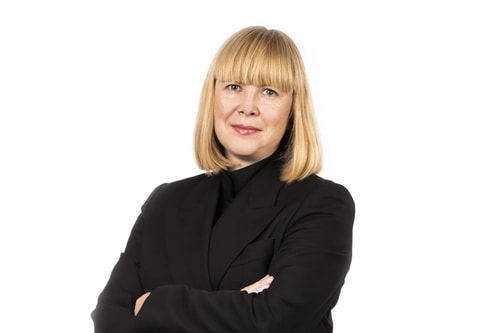 a person with blonde hair wearing a black suit