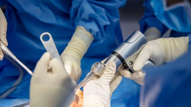 a close-up of hands in gloves holding a surgical instrument